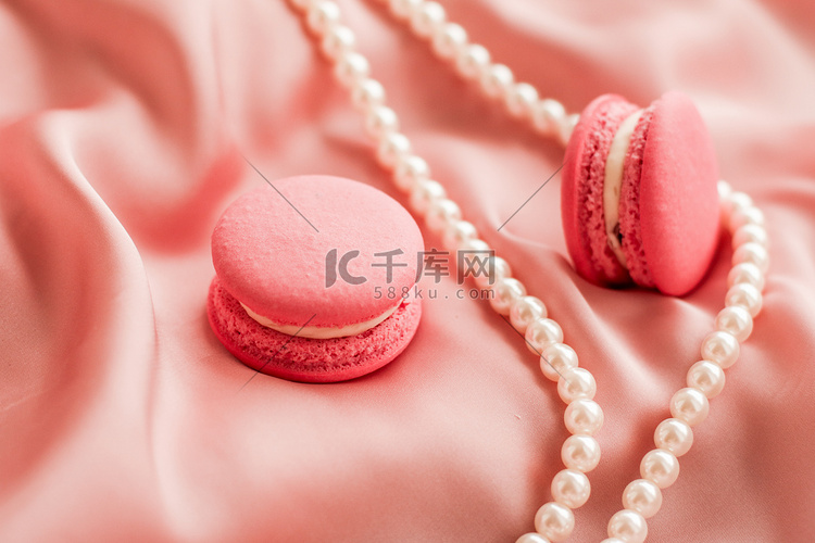 丝绸背景上的甜马卡龙和珍珠首饰