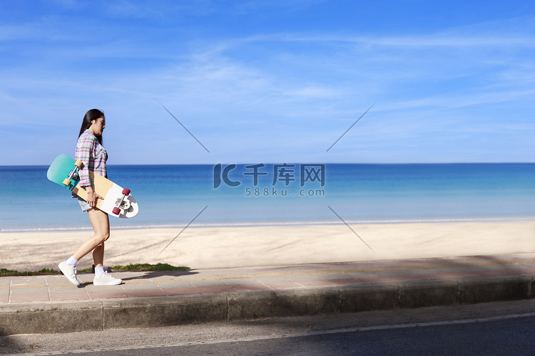 年轻女性带着冲浪滑板在热带海滩