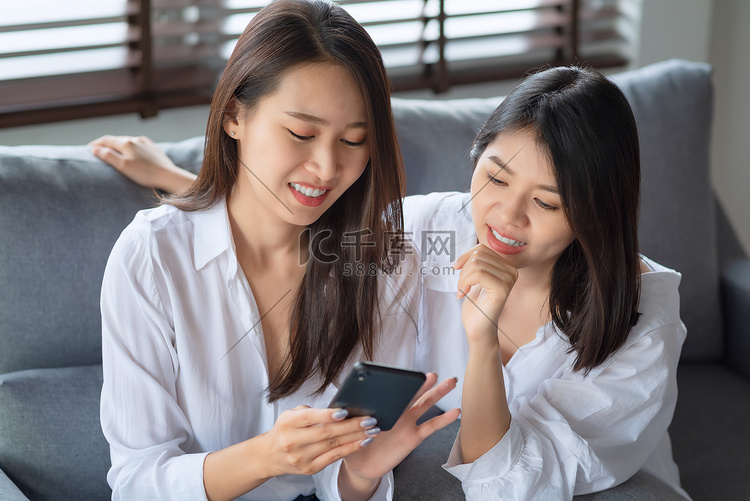 两名亚洲女性喜欢在家看手机照片