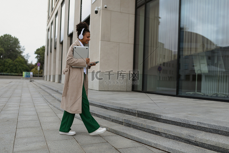 一位戴着耳机、手里拿着笔记本电