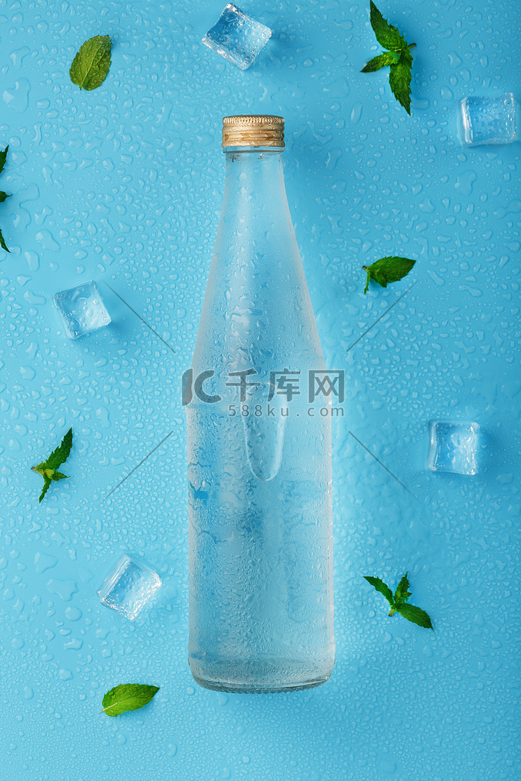 蓝色背景上的冷水瓶、冰块、水滴
