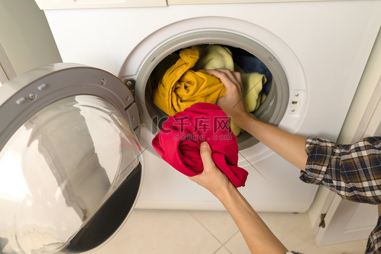 女人把鲜艳的衣服放进洗衣机。