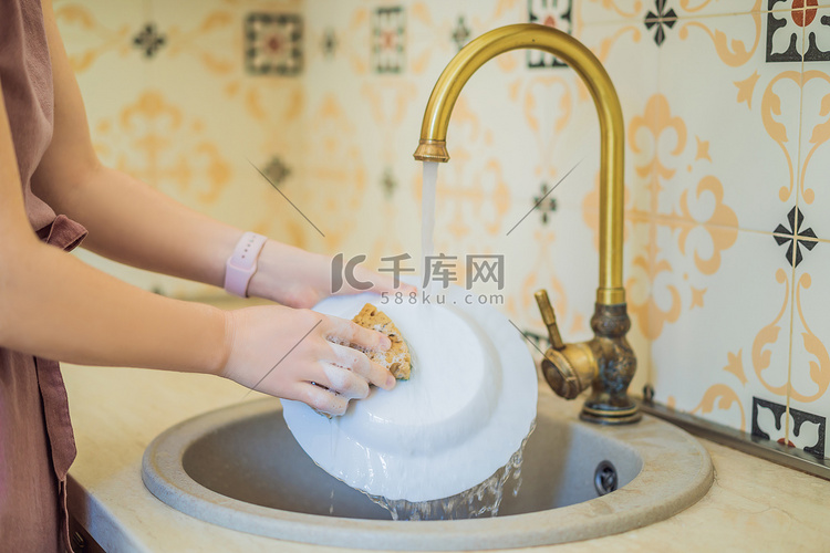 一位年轻女子在水槽里用海绵洗碗