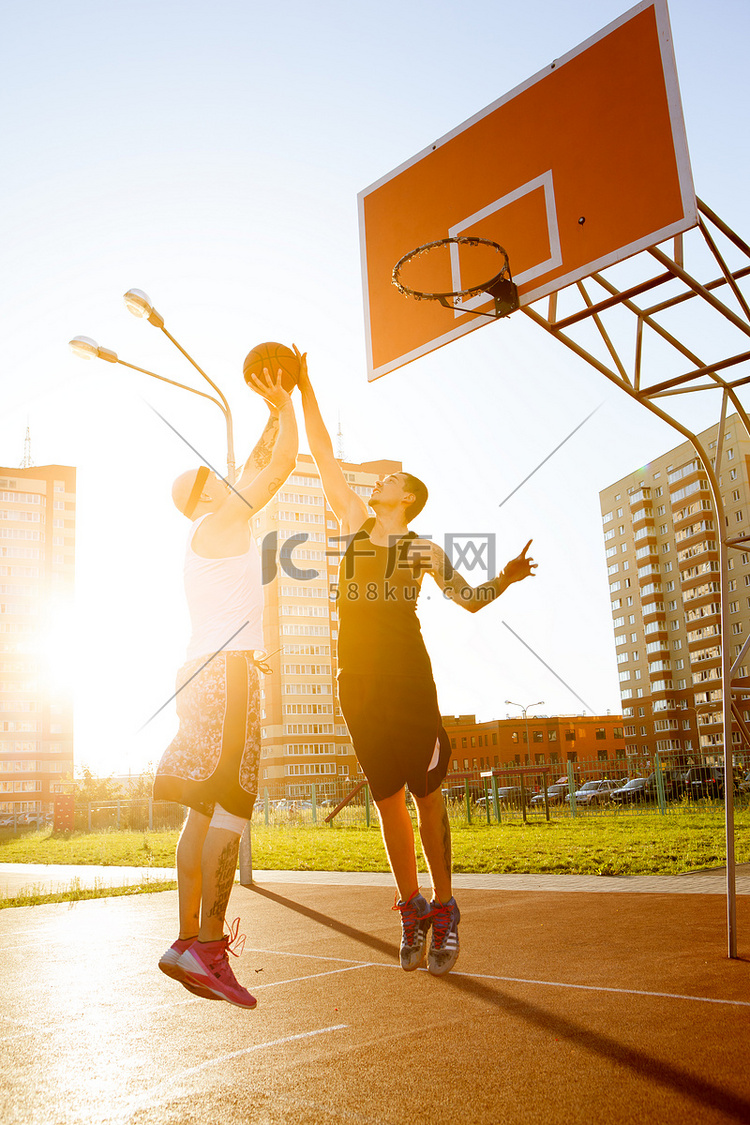 两个人在区运动场打篮球。