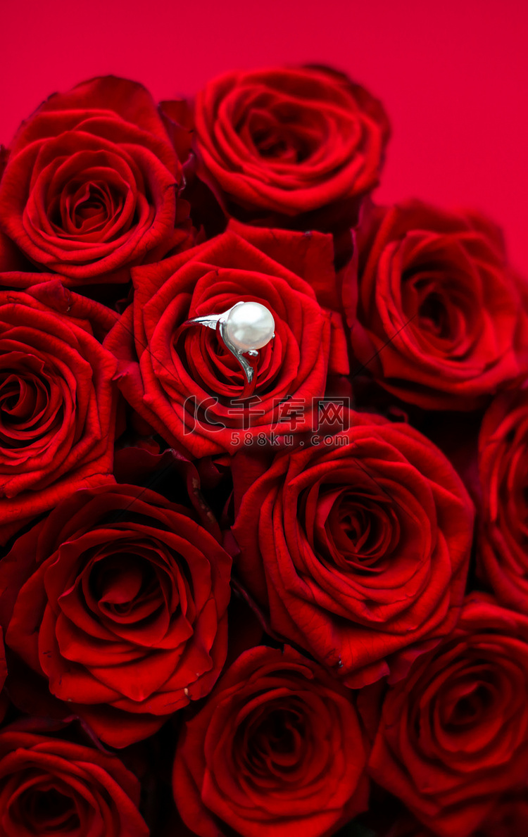 美丽的白金珍珠戒指和红玫瑰花束