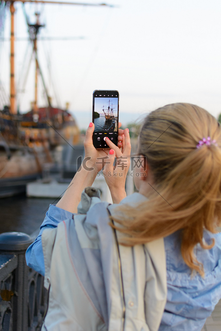在智能手机相机上拍摄帆船的女孩