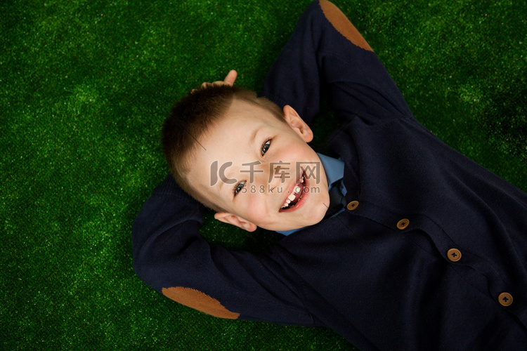 美丽快乐的小男孩躺在绿色背景上