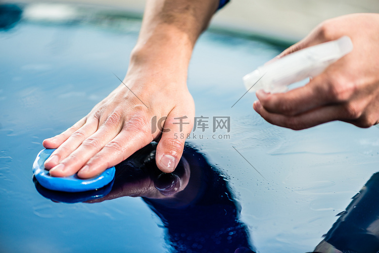 男手在汽车清洗时给蓝色汽车打蜡