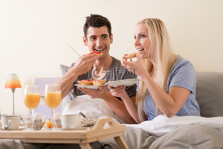 年轻夫妇在床上吃早餐庆祝