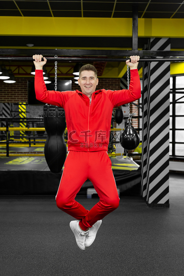 穿着红色运动服的瘦男人在健身房