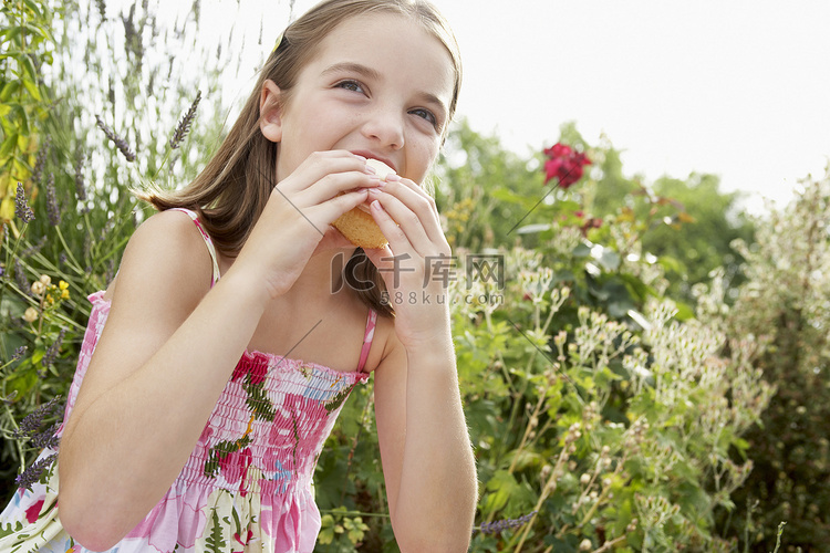 坐在草地上吃纸杯蛋糕的小女孩