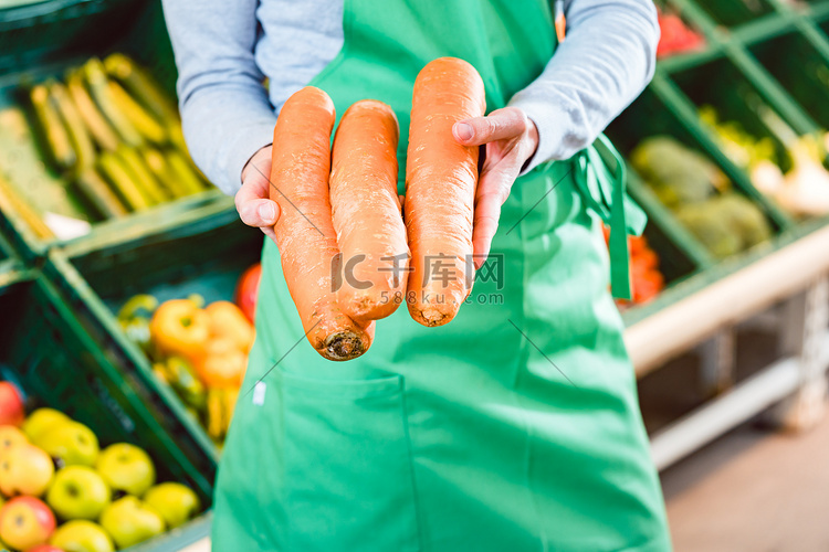 有机超市的女售货员提供新鲜胡萝