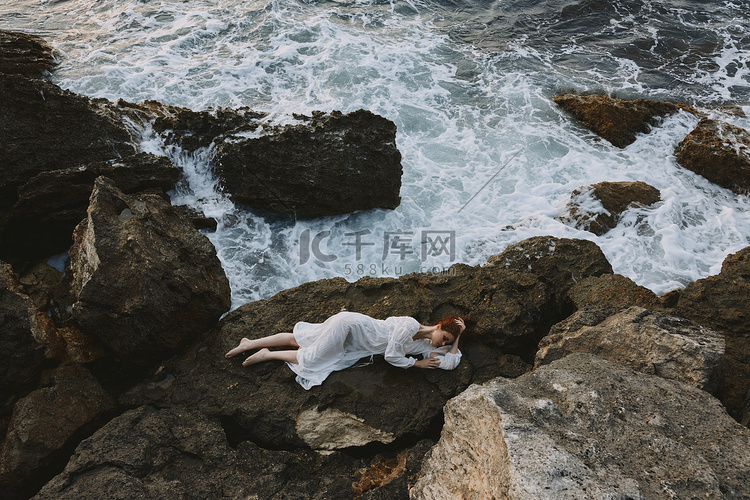 长头发的漂亮女人躺在岩石海岸上