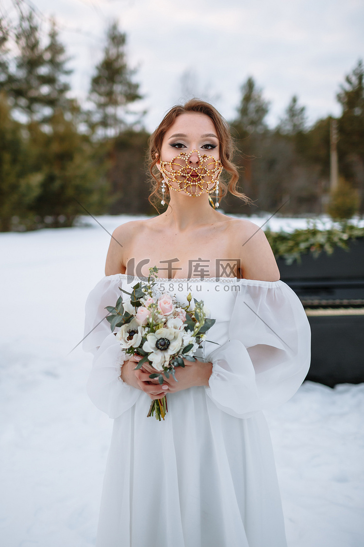 新娘站在白雪覆盖的森林里。
