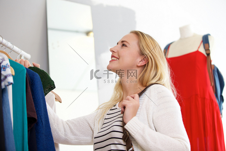 微笑的年轻金发女郎在商店买衣服