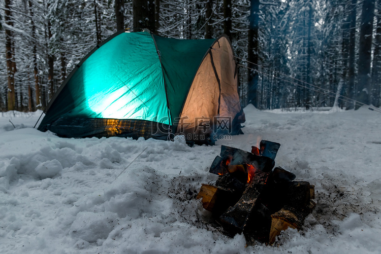 雪中​​的篝火，背景是绿色帐篷