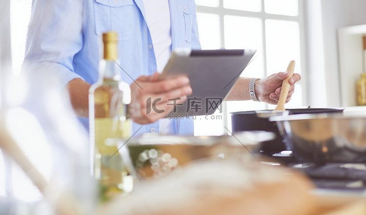 男人在数字平板电脑上遵循食谱，