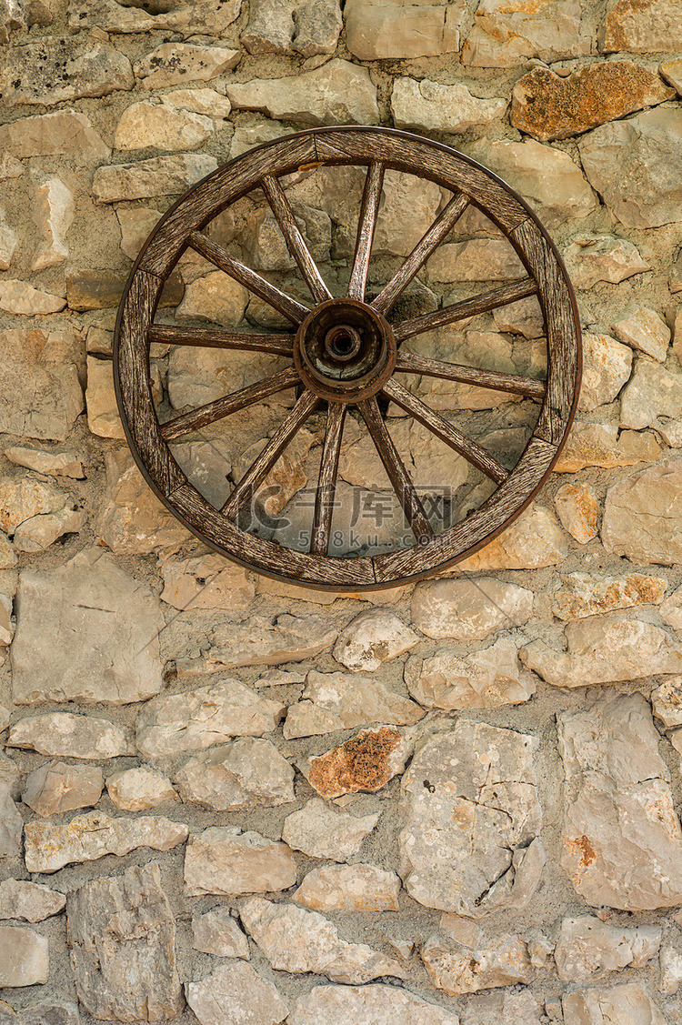 垂悬在农舍老质朴石墙上的车轮