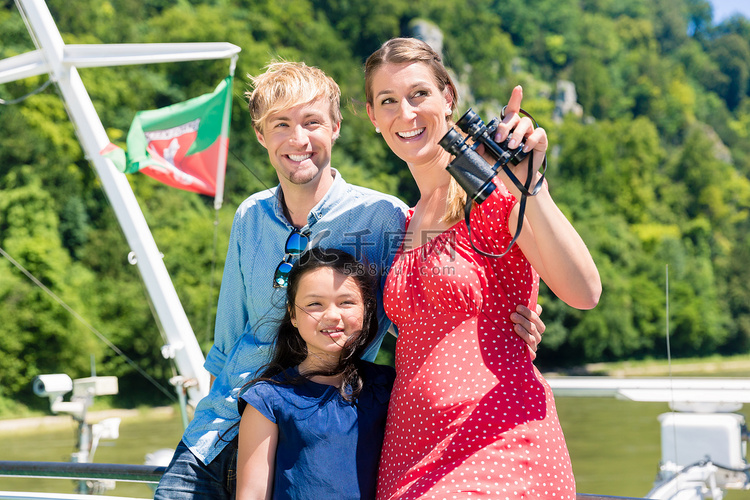 夏季带双筒望远镜的家庭在河上巡