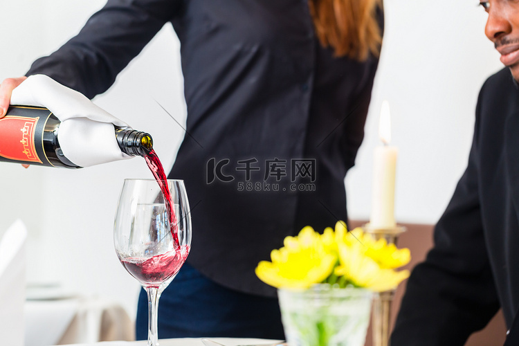 高级餐厅的女服务员在玻璃杯里倒