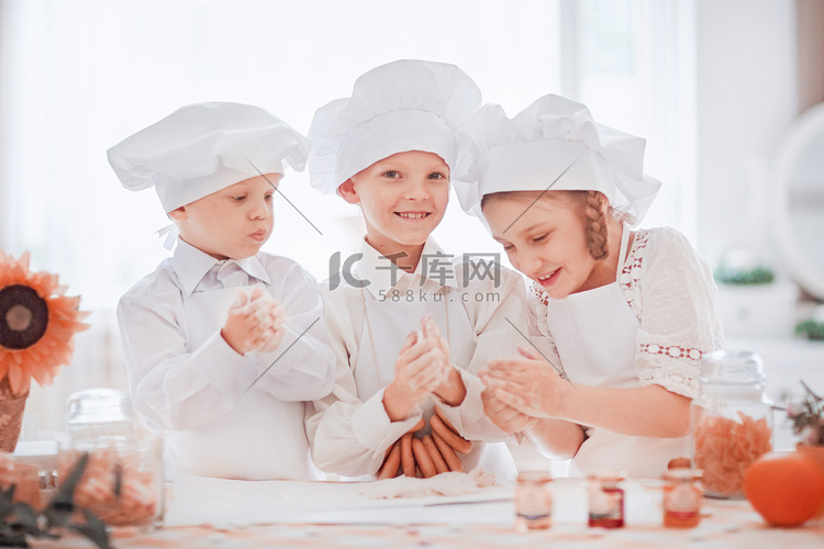 穿着厨师制服的孩子们站在餐桌旁