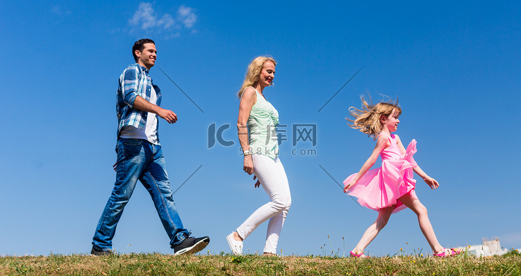 一家人在草地上散步，女儿领头，