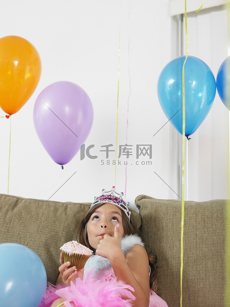 小女孩坐在沙发上，抬头看着气球