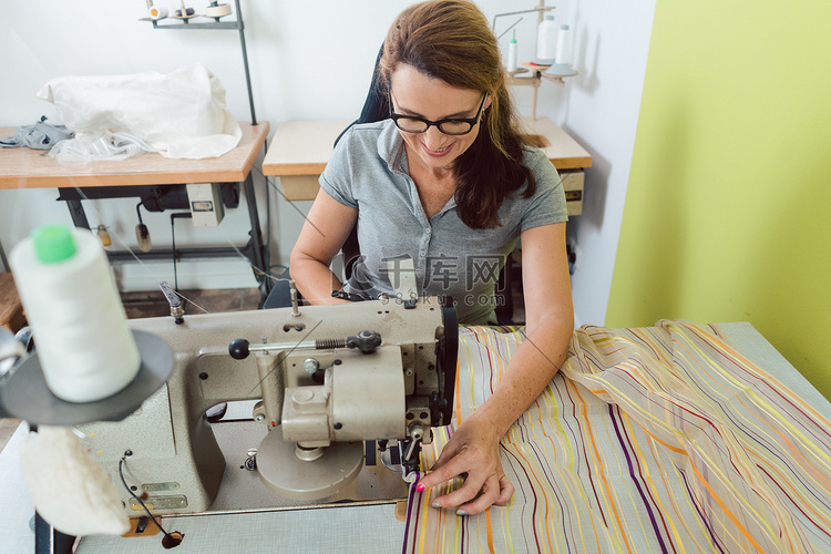 女裁缝在缝纫机上缝制装饰织物