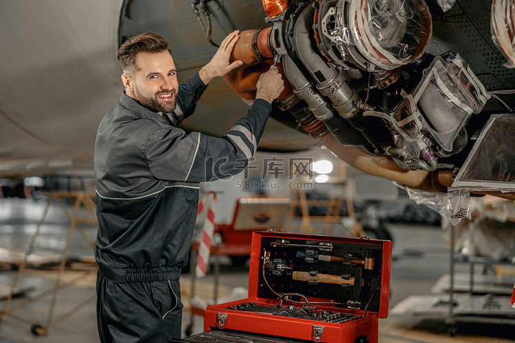 快乐的男性机械师在机库修理飞机