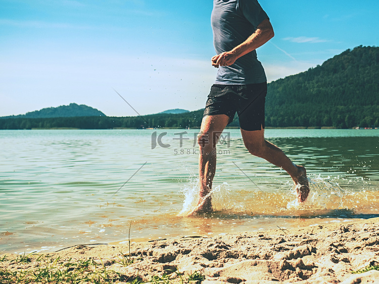 赤脚运动员沿着沙滩在水中奔跑