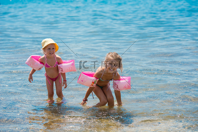 带游泳臂章的小女孩在浅水中玩耍