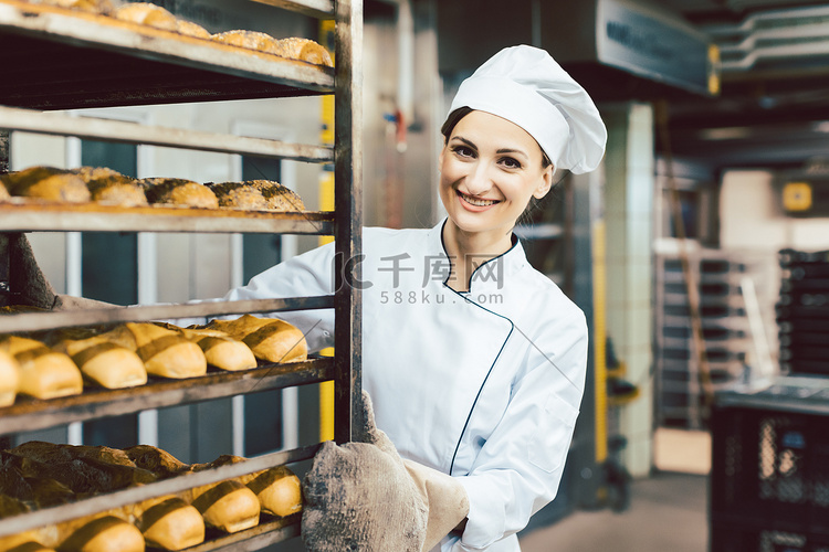面包师的女人在烤炉里用面包推着