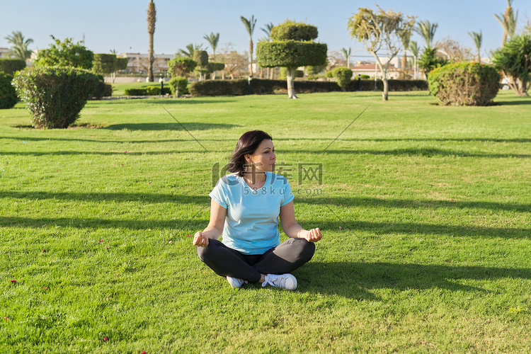 中年妇女盘坐草地上冥想