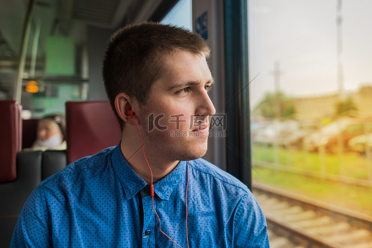 身穿蓝色衬衫、戴着耳机听音乐的