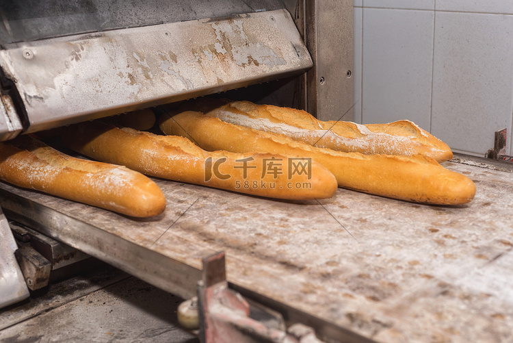 面包师从工业烤箱中取出新鲜出炉