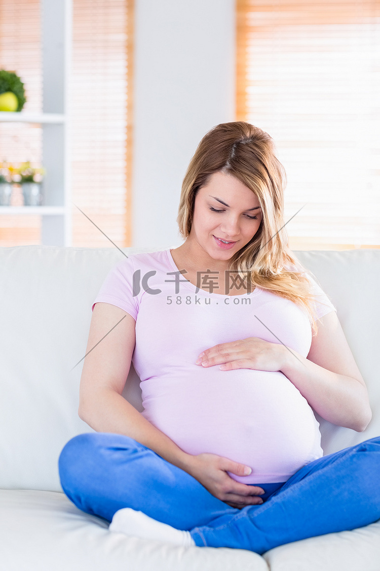 孕妇坐在沙发上触摸她的腹部