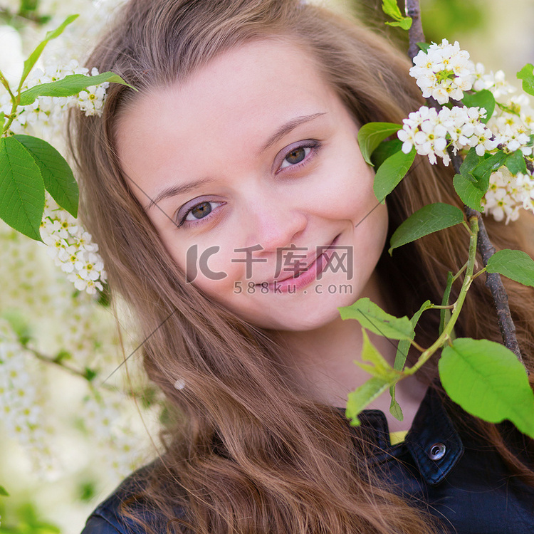 一个女孩的肖像与盛开的鸟樱桃树