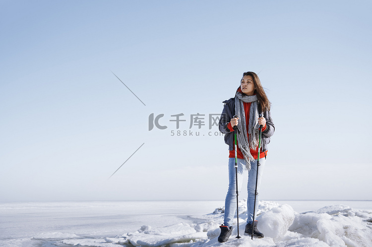 年轻成年女性背着背包和手杖在冰