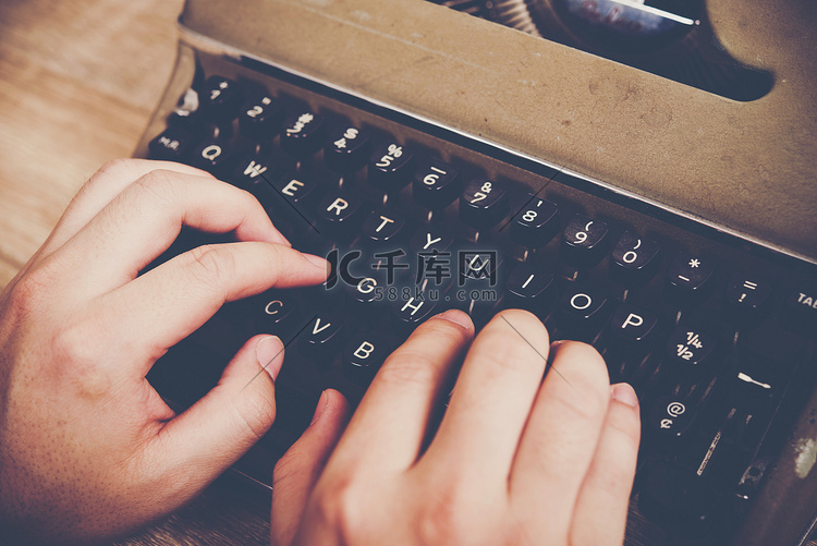 手在木桌上的老式打字机上打字。