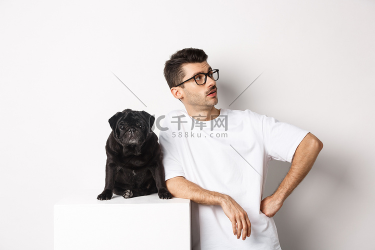 英俊的年轻人站在可爱的黑哈巴狗