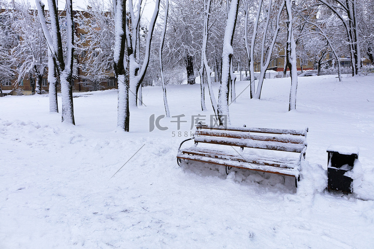 城市公园小巷里的木凳被雪覆盖