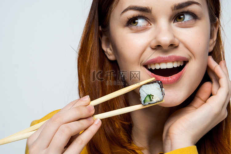 浅色背景下用日本筷子吃寿司的女