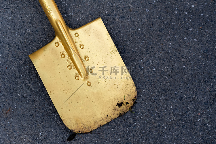 一把金色的铲子躺在柏油路上。开
