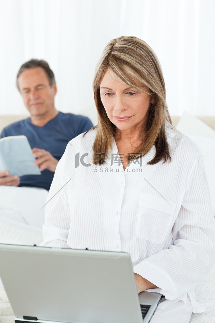 丈夫读书时，女人正在看笔记本电