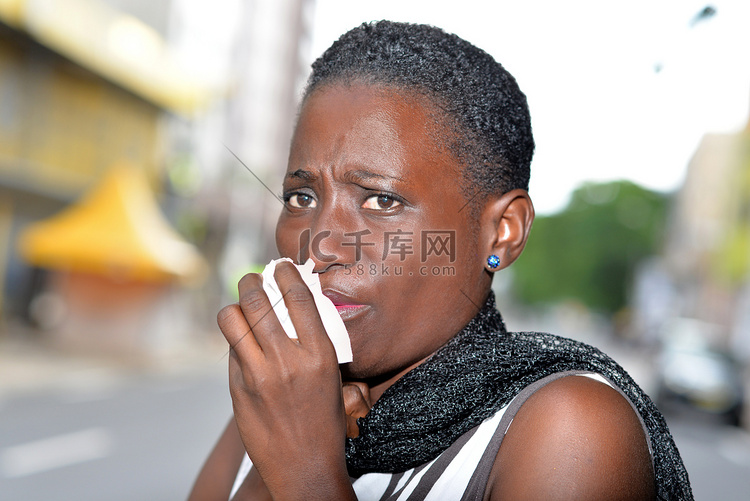 年轻女子在街上边抓边咳嗽。