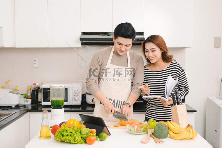 年轻的亚洲夫妇在厨房里切菜和使