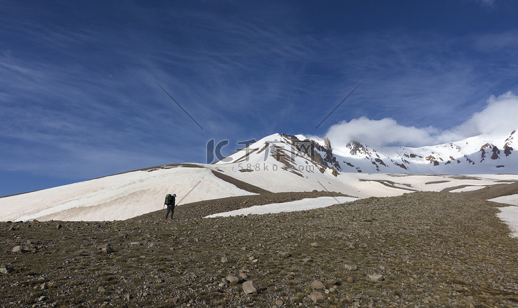 游客爬上山腰到达白雪皑皑的山顶