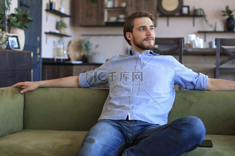 英俊的年轻商人坐在家里的沙发上