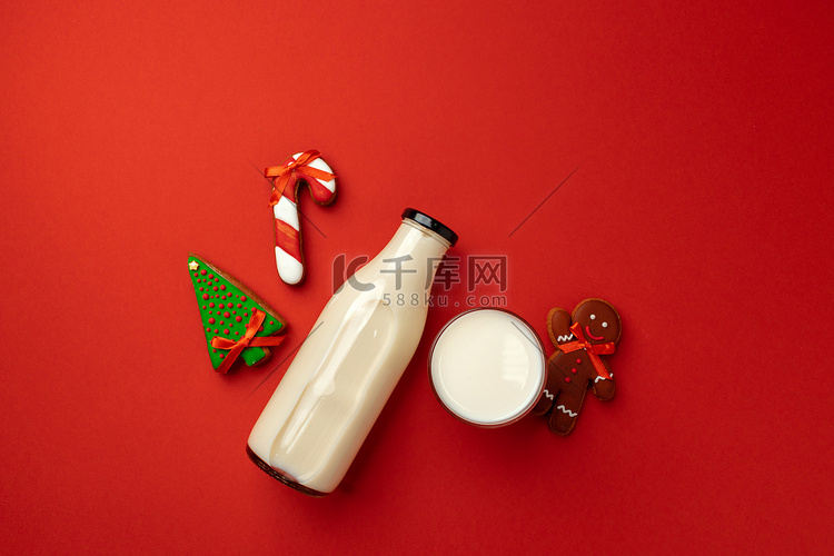 红色背景中的玻璃奶瓶和圣诞姜饼
