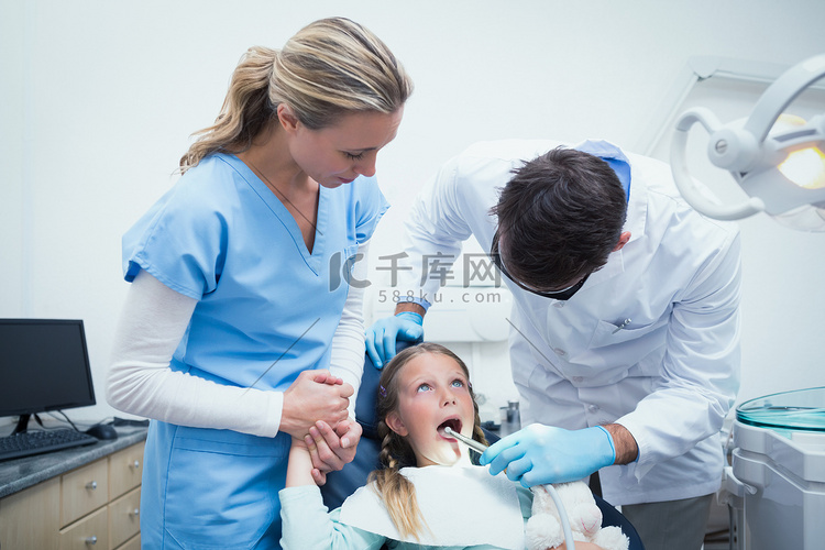 牙医与助理检查女孩的牙齿